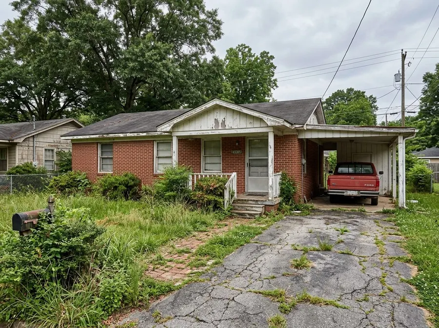 A red brick ranch house with peeling trim, a sagging carport and an overgrown front lawn.